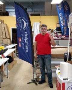 Dolphies Promo branded feather flag on a cross base