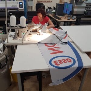 Finishing a printed flag in the Dolphies Promo workshop