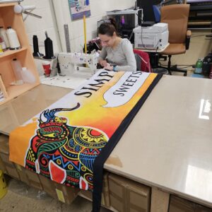 Printed feather flag fabric being sewn at a work table