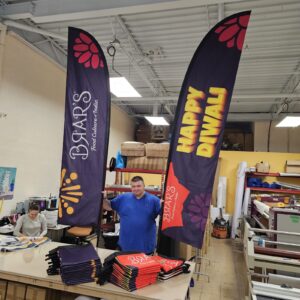 Two dark purple feather flags standing behind a work bench in a print shop