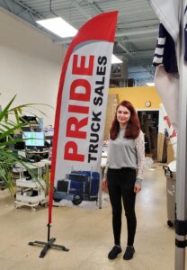 White and red feather flag with a truck graphic on a cross base, indoors