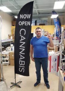 Black feather flag with white lettering on a cross base, indoors