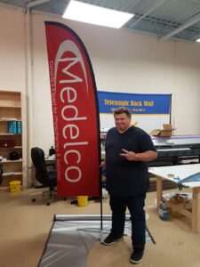Red feather flag with white lettering on a cross base in a print shop