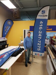 Blue feather flag with a phone number on a cross base in a print shop