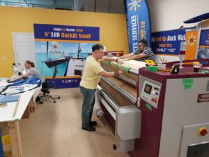 Feather flag fabric being fed through a dye-sublimation heat press