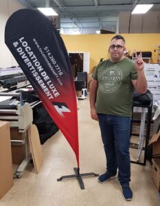 Black and red teardrop flag on a cross base, indoors