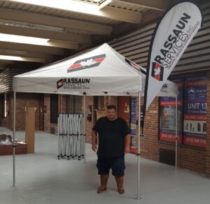 White printed canopy tent with a feather flag attached to one leg, indoors