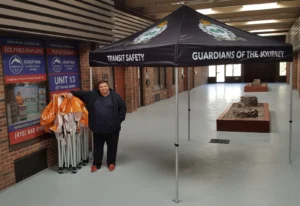 Black printed canopy tent next to folded tent frames, indoors