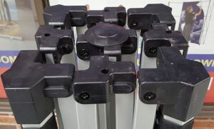 Black corner fittings on top of a folded aluminum tent frame