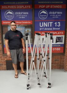 Partly opened aluminum tent frame next to a person