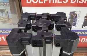 Black corner fittings on a folded aluminum tent frame, seen from above