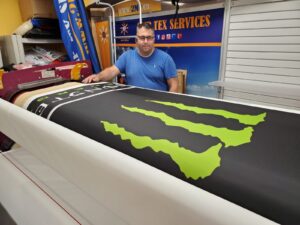 Black canopy fabric with a green print on a heat press roller