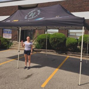 Dark printed canopy tent set up in a parking lot near a building