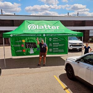 Green printed canopy tent with printed back and side walls in a parking lot