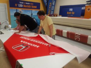 Red printed canopy fabric being finished on a work table