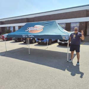 Teal printed canopy tent set up in a parking lot