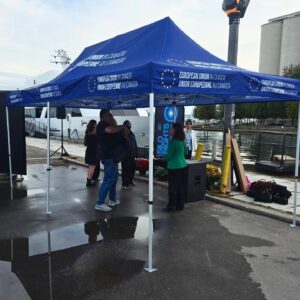 Navy printed canopy tent at an outdoor event on wet pavement