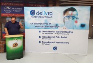 Man at a green printed counter beside a white 10 ft pop up fabric display with a blue logo