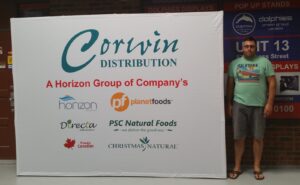 Man beside a white 10 ft pop up fabric display with a green script logo