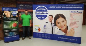 Man beside a white 10 ft pop up fabric display with a security guard photo, next to a roll-up banner