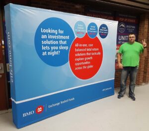 Man beside a blue and white 10 ft pop up fabric display with round red and blue text bubbles
