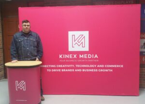 Man at a pink printed counter beside a pink 10 ft pop up fabric display