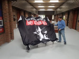 Man unfolding an 8 ft pop up frame with the black graphic attached
