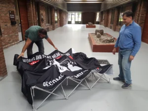 Two men pulling the pop up frame open with the graphic attached, another view