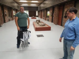 Two men in a hallway, one holding the folded pop up frame