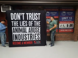 Man beside a black 8 ft pop up fabric display with large white and red lettering