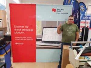 Man beside a red and white 8 ft pop up fabric display with a laptop photo