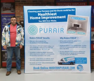 Man beside a light blue 8 ft pop up fabric display with a furnace cleaning service list