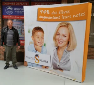 Man beside a white 8 ft pop up fabric display with photos of a boy and a woman