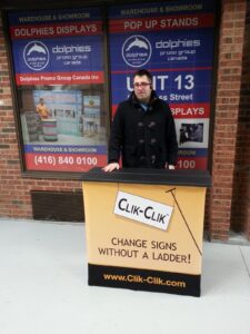 Man behind a pop up fabric counter with a beige graphic and black lettering