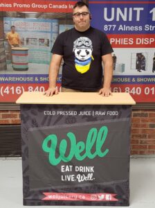 Man behind a pop up fabric counter with a black graphic and green lettering