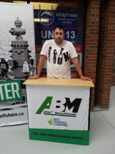 Man behind a pop up fabric counter with a white and green graphic, next to a roll-up banner