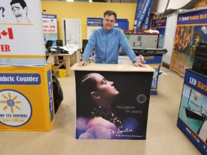 Man behind a pop up fabric counter with a portrait of a woman