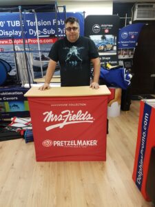 Man behind a red pop up fabric counter with white lettering