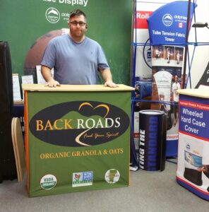 Man behind a green pop up fabric counter with an orange logo