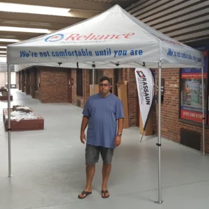White printed canopy tent with a feather flag beside it, indoors