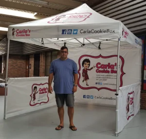 White printed canopy tent with printed half walls on the back and one side, indoors