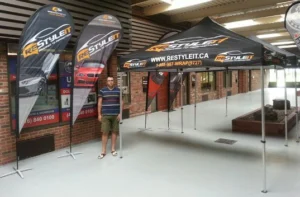 Two black printed canopy tents with teardrop flags, indoors