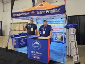Trade show booth under a printed canopy tent with a printed counter