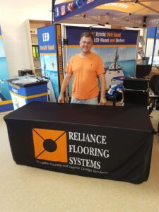 Black fitted table cover with an orange logo and white text