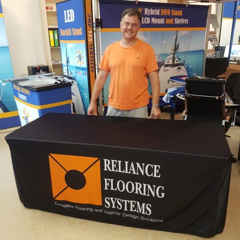 Black fitted table cover with an orange logo and white text