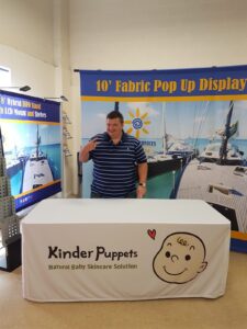 White fitted table cover with a cartoon face and black text