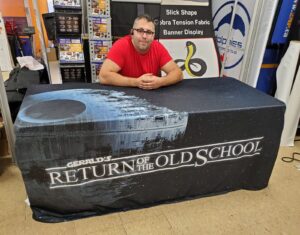 Black fitted table cover with a space photo and white lettering