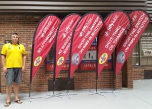 Five red custom printed teardrop flags on cross bases in a showroom