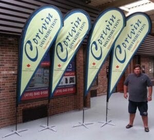 Four cream and navy custom printed teardrop flags on cross bases in a showroom
