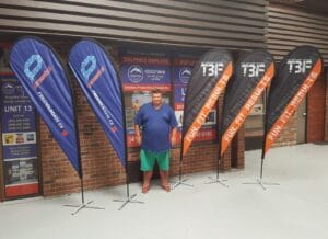 Five custom printed teardrop flags, two blue and three black, on cross bases